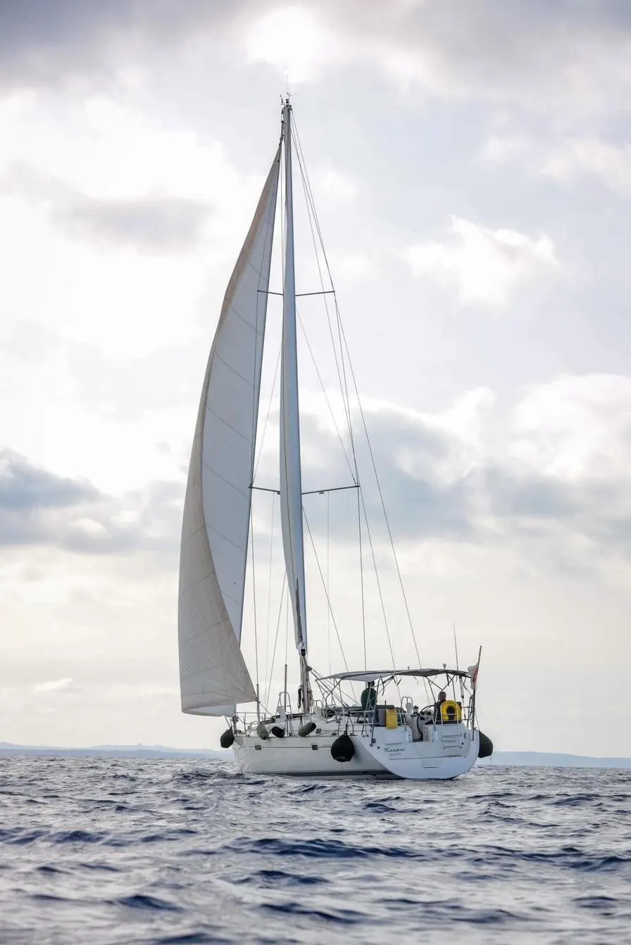 Beneteau 50 sailing with white sails against a bright sky
